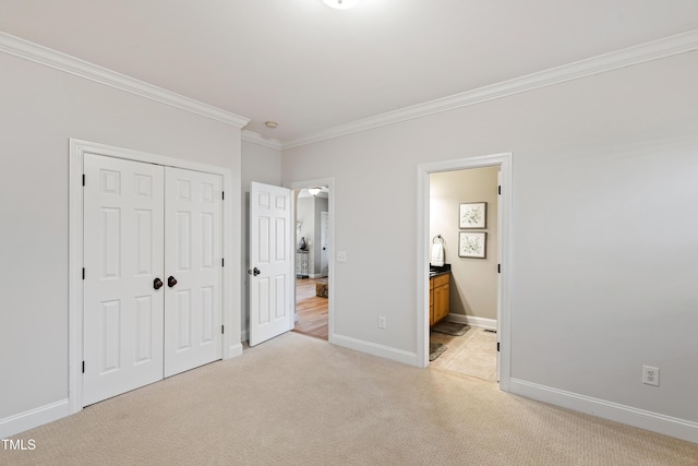 unfurnished bedroom featuring connected bathroom, light carpet, baseboards, ornamental molding, and a closet