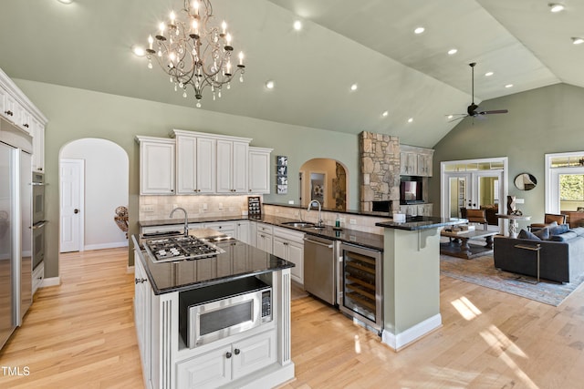 kitchen with appliances with stainless steel finishes, arched walkways, beverage cooler, and open floor plan