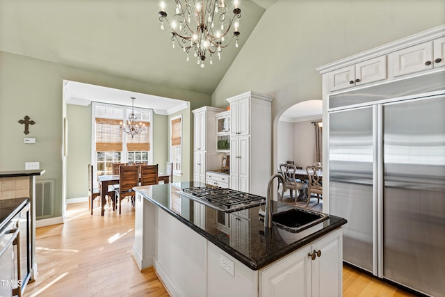 kitchen with arched walkways, visible vents, a center island, stainless steel appliances, and a sink