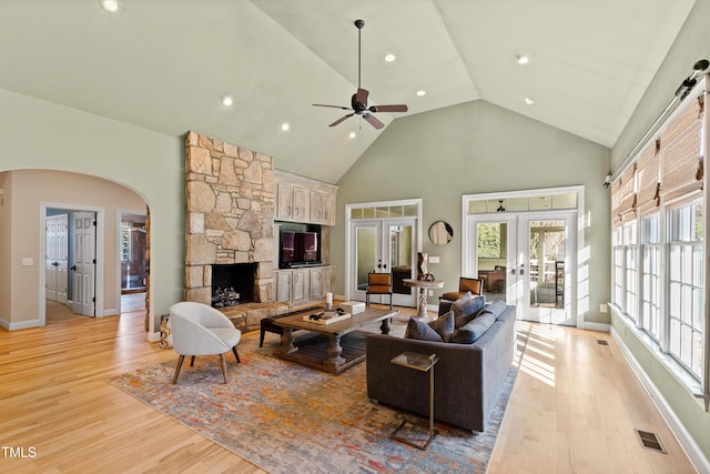 living area featuring light wood finished floors, french doors, arched walkways, and visible vents