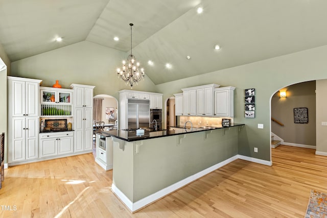 kitchen featuring arched walkways, a peninsula, appliances with stainless steel finishes, and white cabinetry