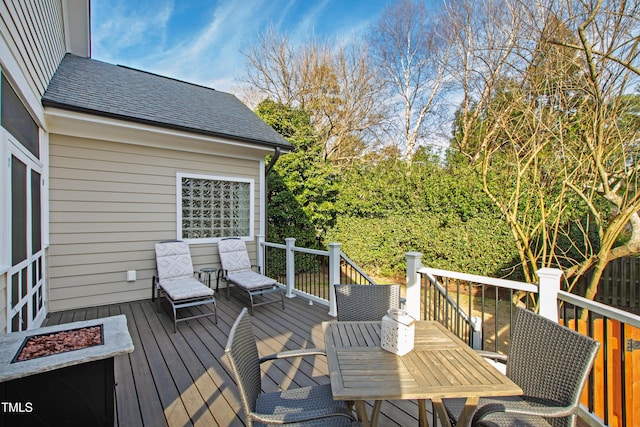 wooden deck featuring outdoor dining area and a fire pit