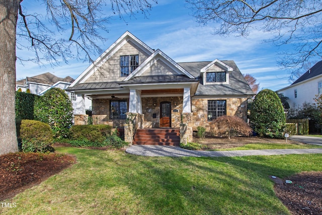 craftsman-style home featuring covered porch, stone siding, and a front lawn