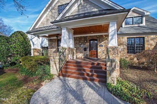 view of front facade with stone siding, covered porch, metal roof, and a standing seam roof