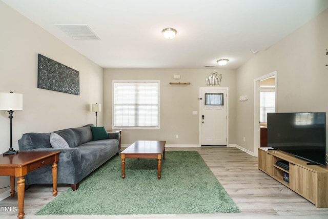 living room featuring light wood-style floors, baseboards, and visible vents