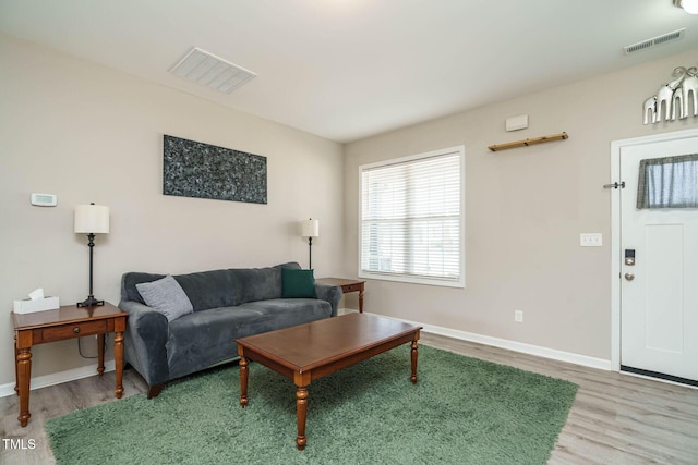 living room featuring visible vents, baseboards, and wood finished floors