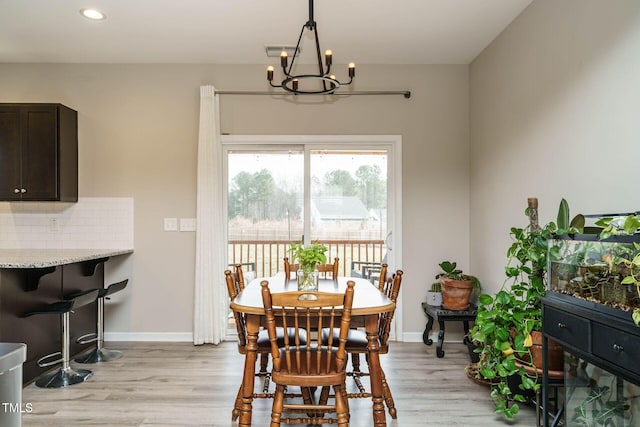 dining area with a notable chandelier, light wood finished floors, visible vents, and baseboards