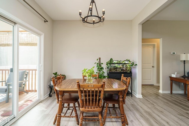 dining space with light wood-type flooring, baseboards, and a notable chandelier