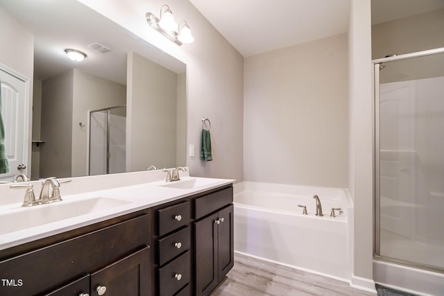 full bath featuring a garden tub, a shower stall, a sink, and wood finished floors