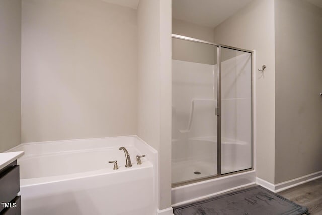 bathroom with a stall shower, baseboards, a garden tub, and vanity