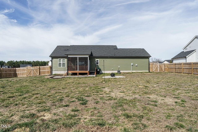 rear view of property featuring a sunroom, a fenced backyard, a gate, and a lawn