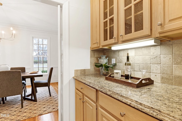 kitchen with wood finished floors, light stone countertops, light brown cabinetry, tasteful backsplash, and crown molding