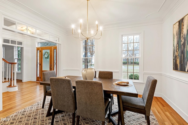 dining area with ornamental molding, light wood-style flooring, and a notable chandelier