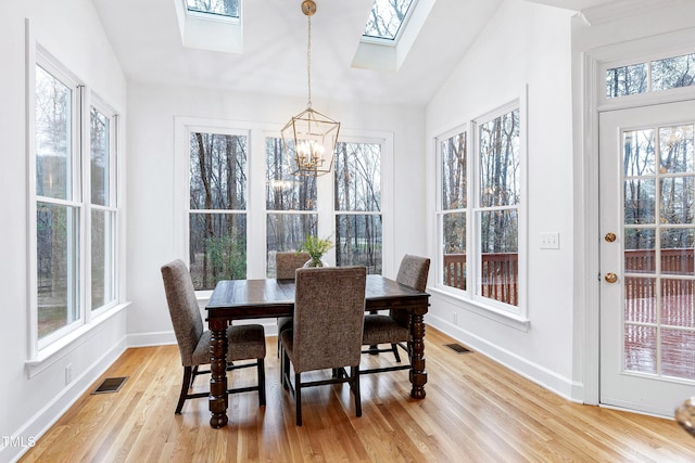 sunroom / solarium featuring lofted ceiling with skylight, visible vents, and a chandelier