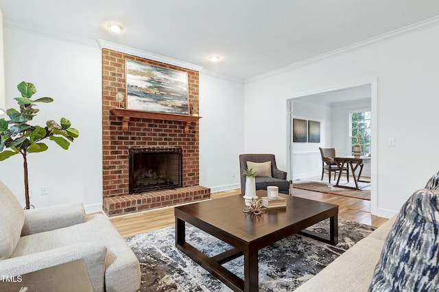 living area with a brick fireplace, crown molding, baseboards, and wood finished floors