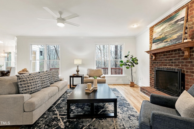 living room with plenty of natural light, a brick fireplace, crown molding, and wood finished floors