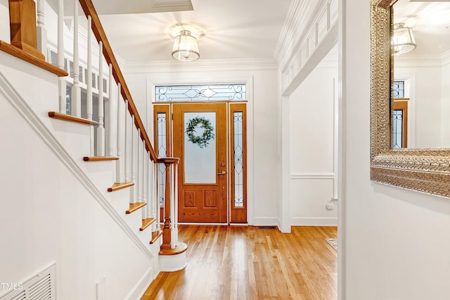 foyer featuring baseboards, visible vents, crown molding, and light wood finished floors