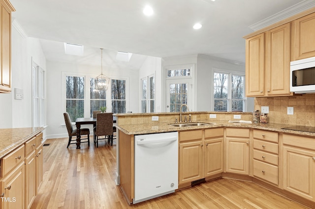 kitchen featuring light brown cabinets, light wood-style flooring, a peninsula, white appliances, and a sink