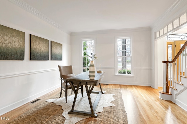 office area featuring ornamental molding, light wood-type flooring, visible vents, and baseboards