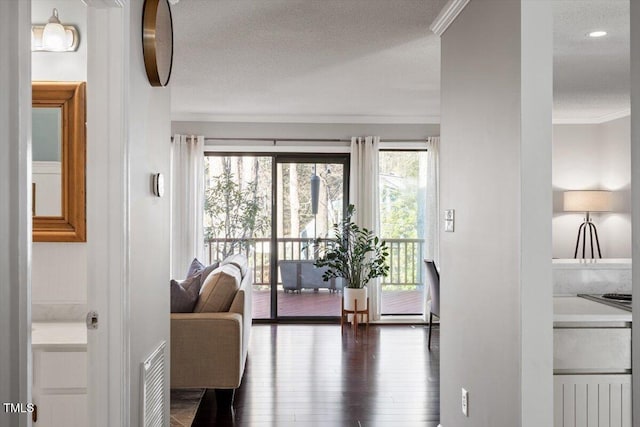 interior space with crown molding, visible vents, dark wood finished floors, and a textured ceiling