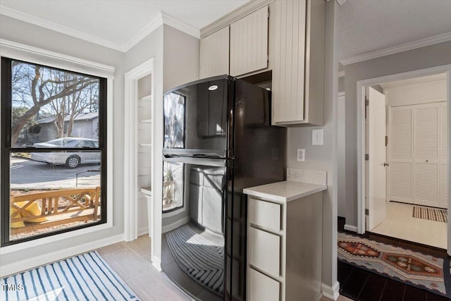 kitchen with baseboards, light countertops, crown molding, and freestanding refrigerator