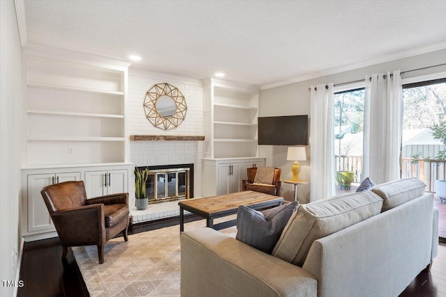 living room featuring a brick fireplace, built in shelves, ornamental molding, and a textured ceiling