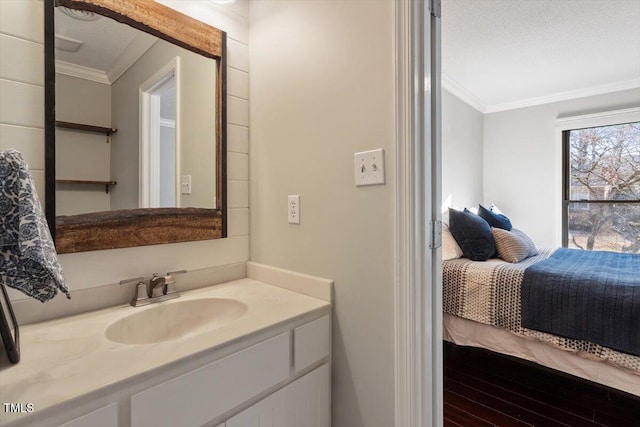 bathroom with a textured ceiling, ornamental molding, wood finished floors, and vanity