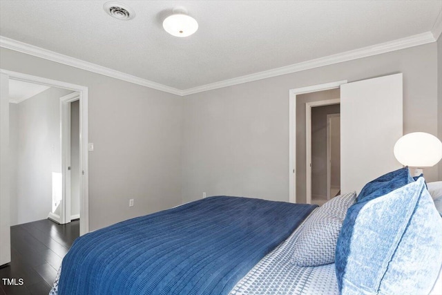 bedroom featuring crown molding, visible vents, and wood finished floors