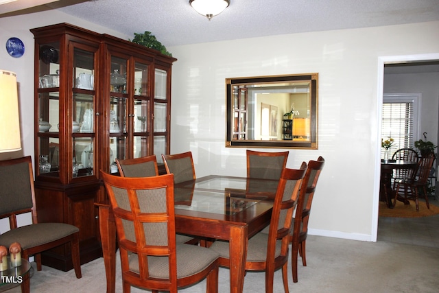 dining area with baseboards, a textured ceiling, and carpet flooring