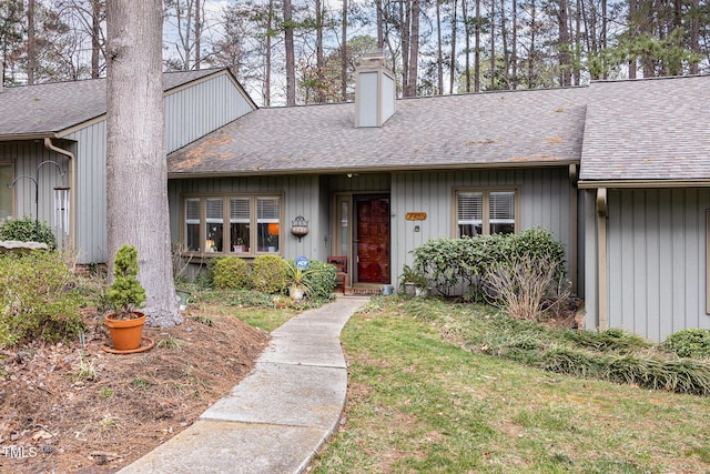 view of front of home featuring a shingled roof, a front yard, and a chimney