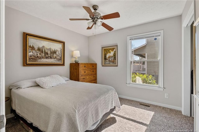 bedroom featuring a textured ceiling, carpet floors, multiple windows, and baseboards