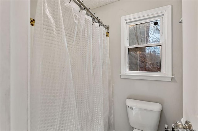 bathroom featuring a shower with shower curtain, a textured ceiling, and toilet