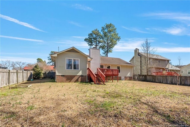 rear view of house featuring a chimney, a fenced backyard, a lawn, and a deck