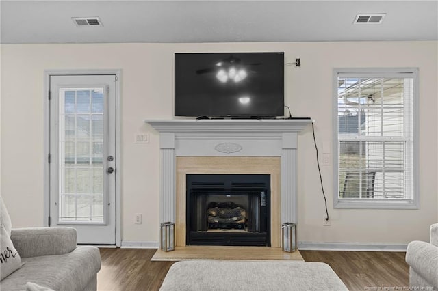 living area featuring a wealth of natural light, visible vents, and wood finished floors