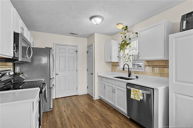 kitchen featuring white cabinets, appliances with stainless steel finishes, light countertops, and a sink