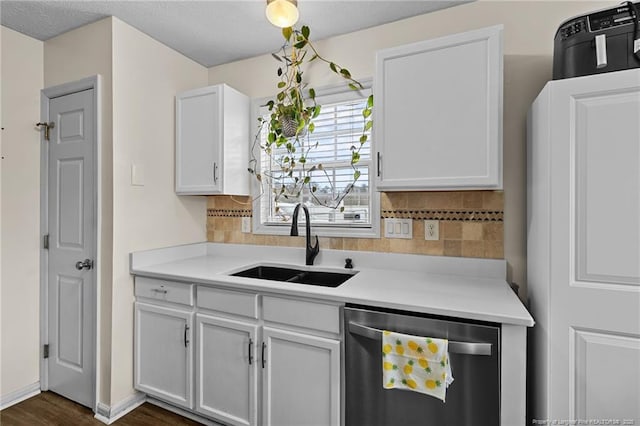 kitchen featuring decorative backsplash, light countertops, dishwasher, and a sink