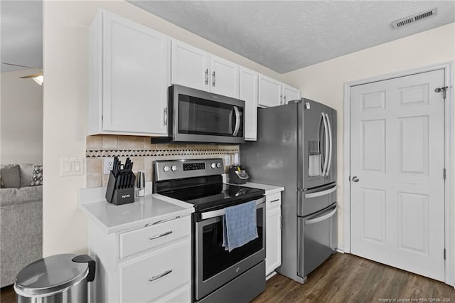 kitchen with visible vents, dark wood-style floors, appliances with stainless steel finishes, light countertops, and white cabinetry