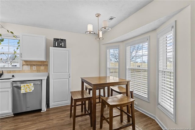 dining room featuring a textured ceiling, visible vents, baseboards, dark wood-style floors, and an inviting chandelier