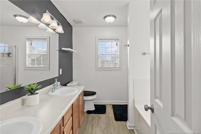 full bathroom with wood finished floors, plenty of natural light, a sink, and toilet