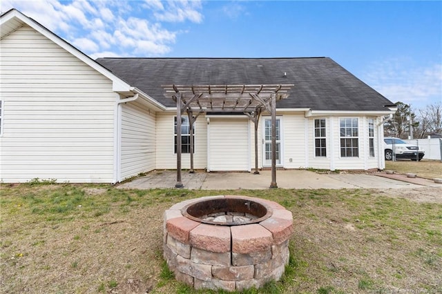 rear view of property with a yard, a shingled roof, an outdoor fire pit, a patio area, and a pergola