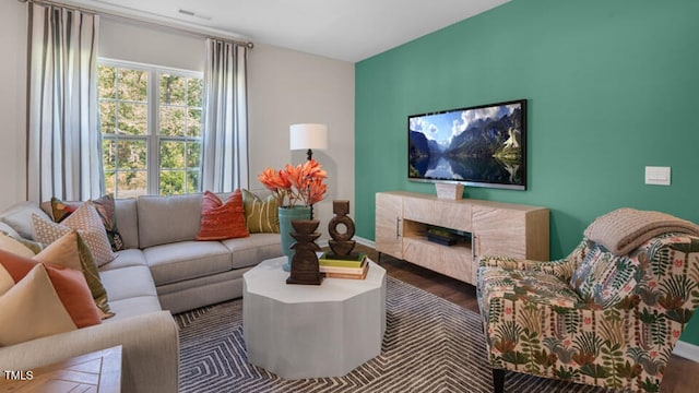 living area with a high end fireplace, visible vents, baseboards, and wood finished floors