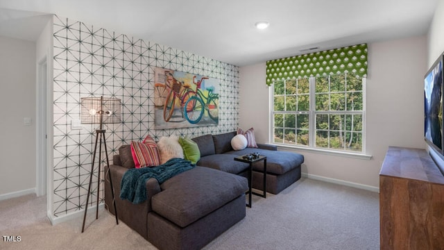 carpeted living room featuring an accent wall and baseboards