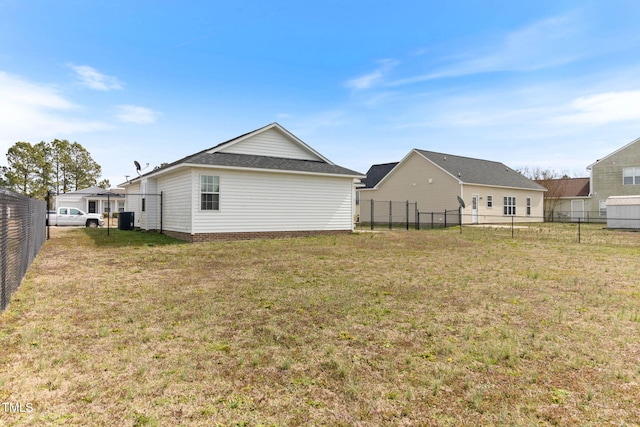 rear view of house featuring cooling unit, a fenced backyard, and a yard