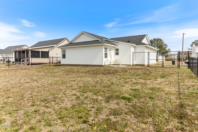 back of property featuring a sunroom, a gate, fence, and a yard