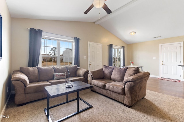 living area featuring a healthy amount of sunlight, baseboards, lofted ceiling with beams, and visible vents