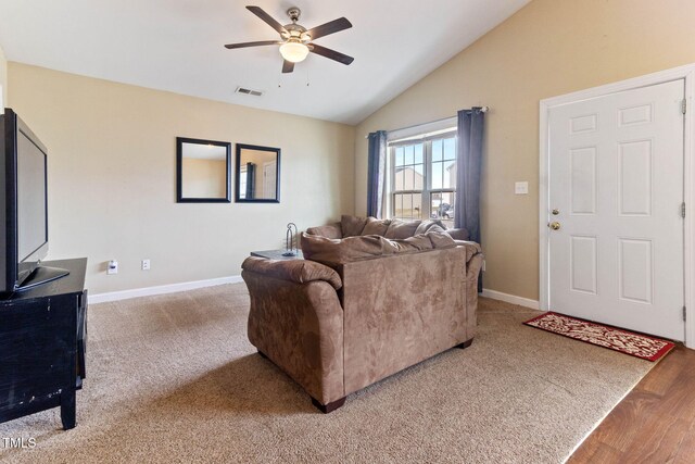 carpeted living area with baseboards, visible vents, vaulted ceiling, and a ceiling fan