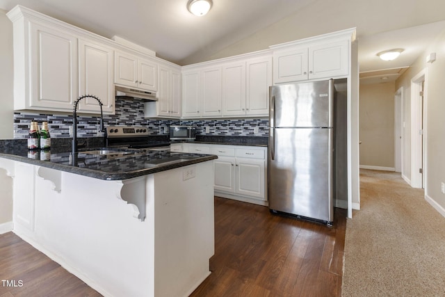 kitchen featuring white cabinets, lofted ceiling, appliances with stainless steel finishes, a peninsula, and under cabinet range hood