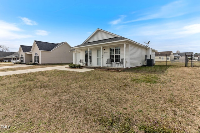 view of front of property with cooling unit, covered porch, fence, concrete driveway, and a front yard