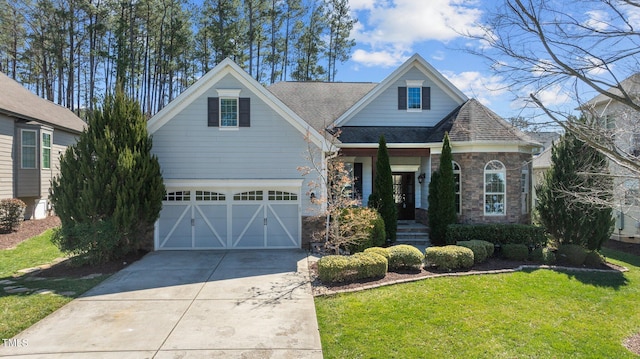 view of front of home with stone siding, concrete driveway, a front yard, and a shingled roof