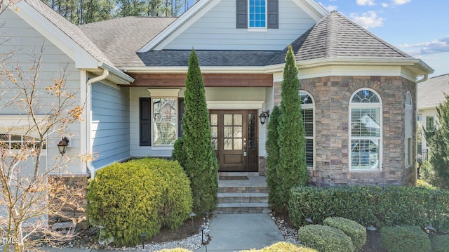 entrance to property featuring stone siding and a shingled roof